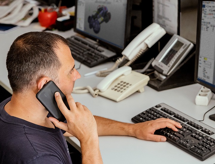 man talking on cell phone with his hand on a keyboard